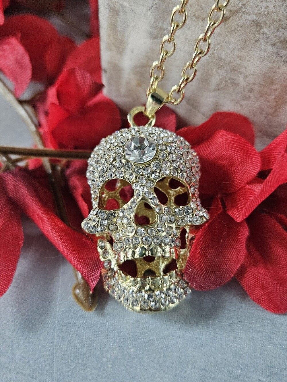 Gold-colored chain necklace featuring a large, rhinestone-encrusted skull pendan